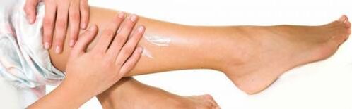 Applying medicinal cream to legs with varicose veins
